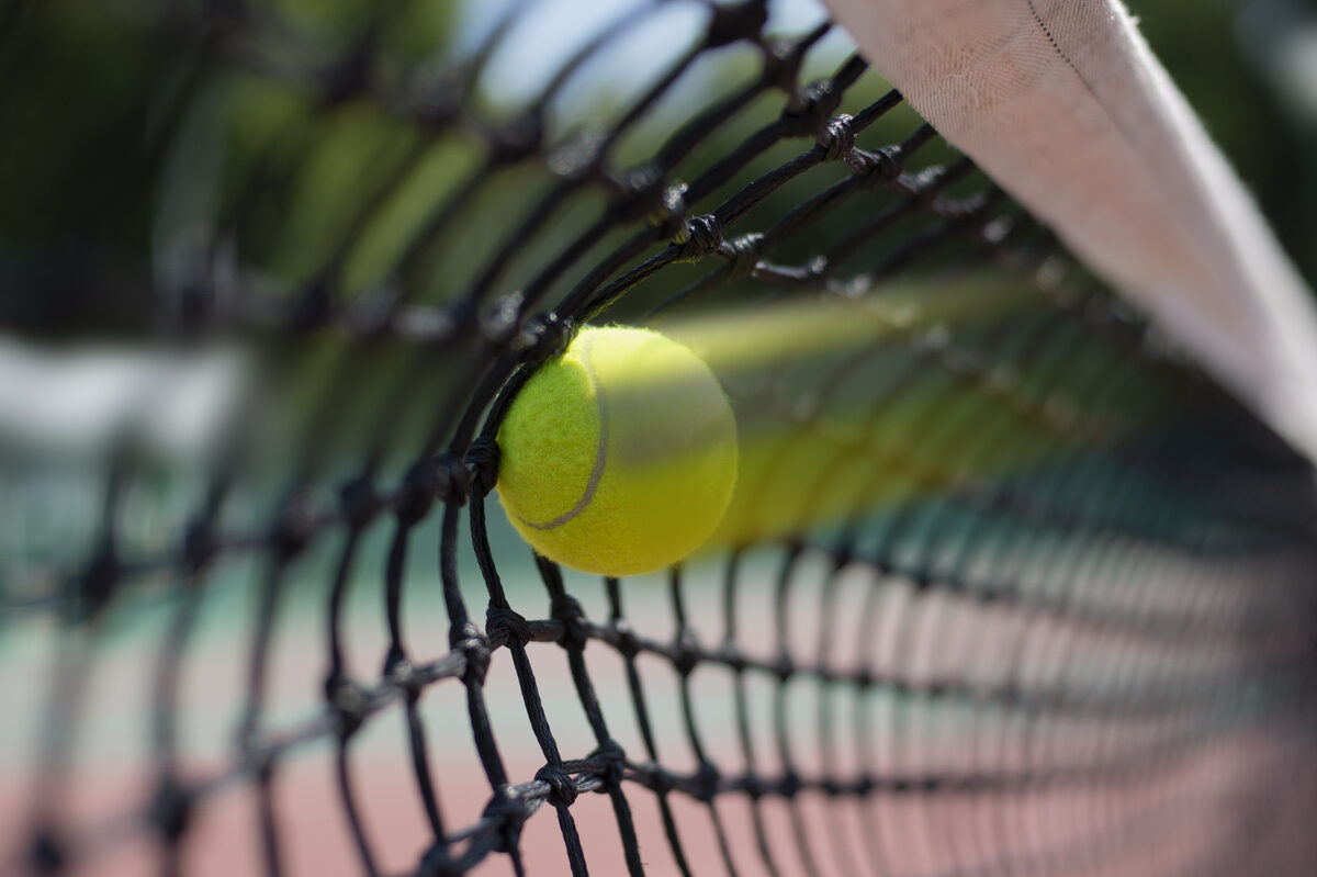 Tennis ball hits in the net during game.